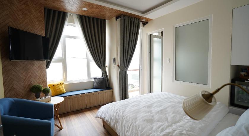 a bedroom with a white bedspread and a large window, Homeland Hotel in Dalat