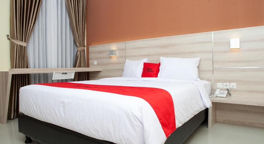 a bed with a white comforter and pillows in a room, RedDoorz Plus near Pasundan University in Bandung