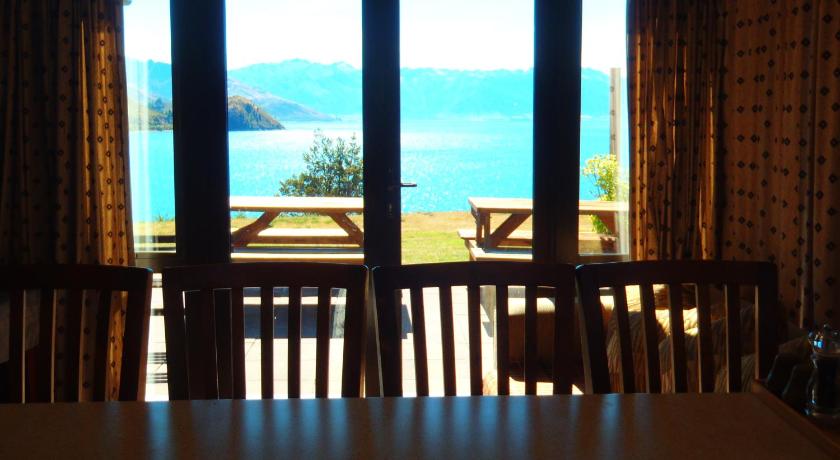 a dining room table in front of a large window, Lakefront Bellevue Lake Hawea Wanaka in Wanaka