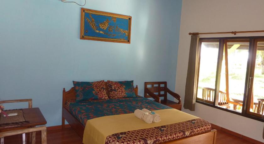 a bedroom with a bed, a desk, and a painting on the wall, Java Lagoon Hotel in Sukaresik