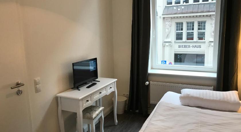 a bedroom with a bed and a desk with a laptop, Hotel Fame am Hauptbahnhof in Hamburg