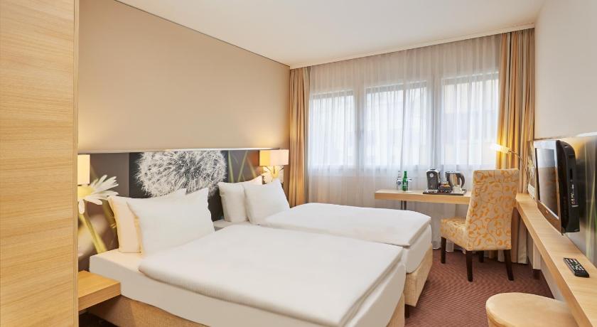 a hotel room with a large bed and a large window, H+ Hotel Zürich in Zürich
