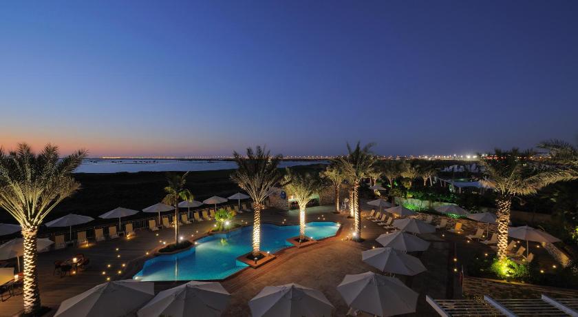 a beach filled with lots of umbrellas and palm trees, Radisson Blu Hotel Abu Dhabi Yas Island in Abu Dhabi