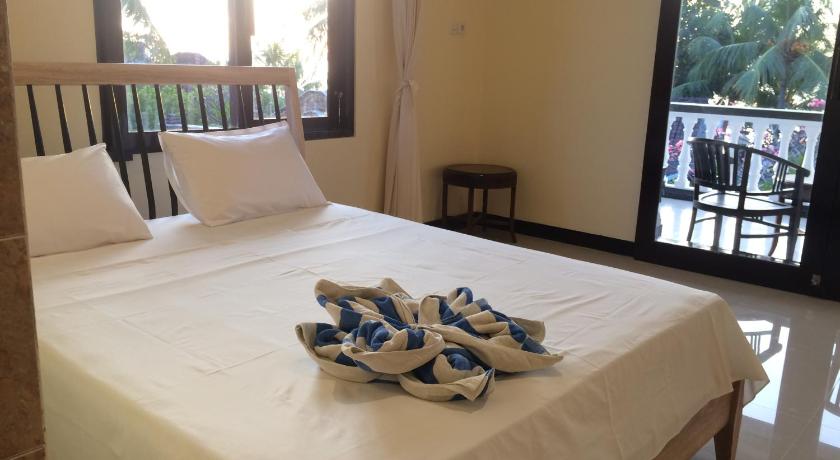 a bed with a pair of blue and white towels on top of it, Mandhara Chico Bungalow in Bali