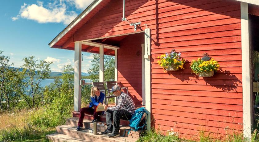 two people sitting on a bench in front of a house, Kilpisjarven Retkeilykeskus Cottages in Kilpisjarvi