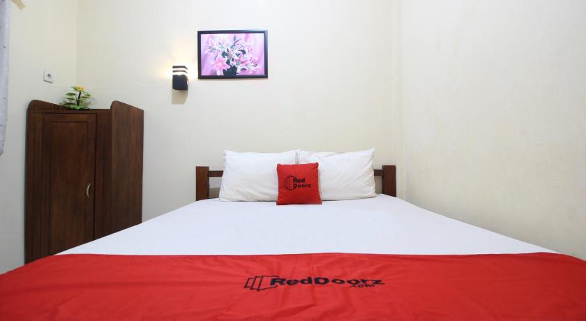 a bed with a white comforter and pillows, RedDoorz @ Jalan Parangtritis in Yogyakarta
