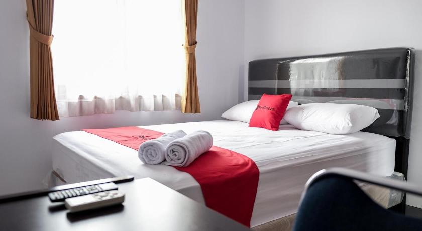a bed in a room with a white bedspread, RedDoorz near Supermall Karawaci 2 in Tangerang