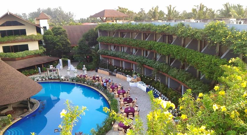 a beach with a pool, chairs, tables and umbrellas, Uday Suites - The Garden Hotel in Thiruvananthapuram