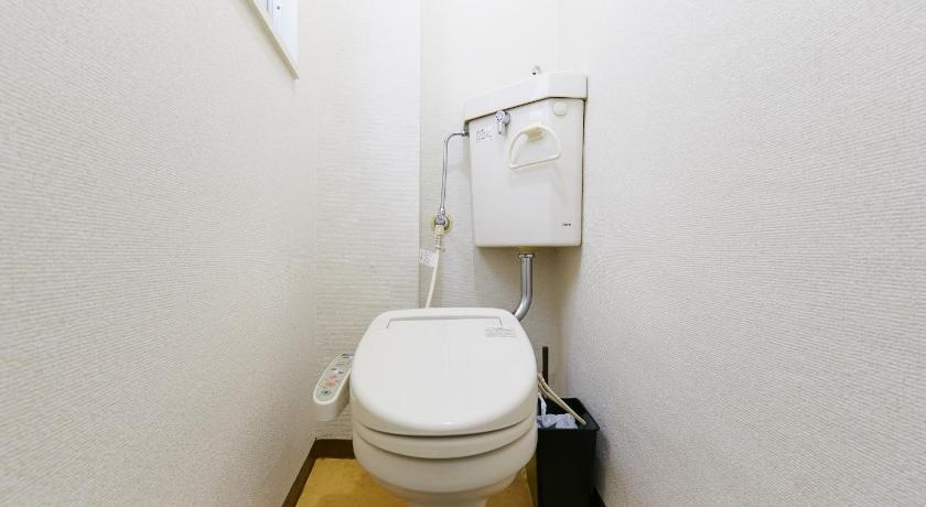 a white toilet sitting next to a white wall, Haneda Lex House in Tokyo