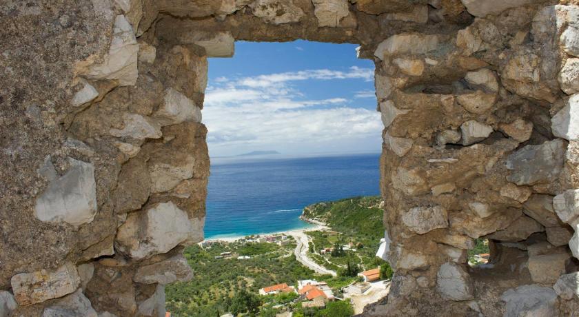 a stone wall with a view of the ocean, Himara Hostel in Vlora