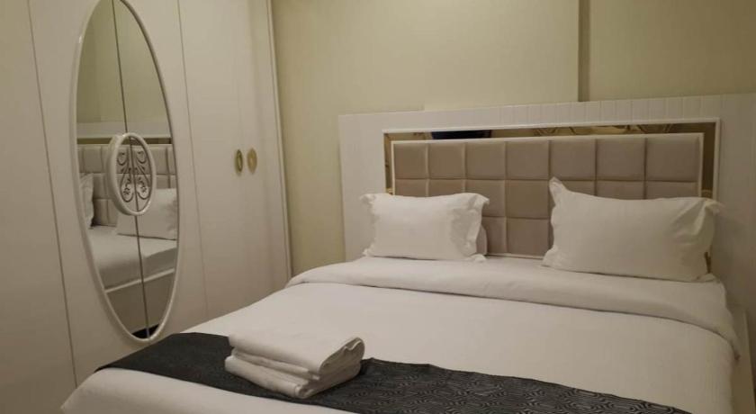 a white bed sitting in a bedroom next to a window, Reef Hotel Apartments 1 in Ajman