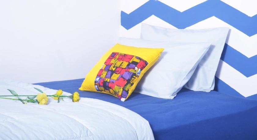 a bed with a blue and yellow blanket and a blue and yellow pillow, Cihampelas Homestay in Bandung