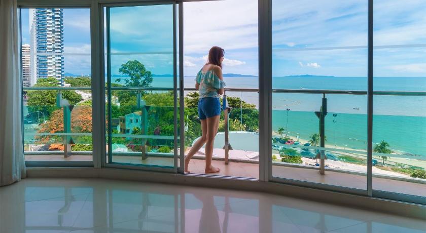 a woman standing in front of a window looking at the ocean, Royal Beach View Suites in Pattaya