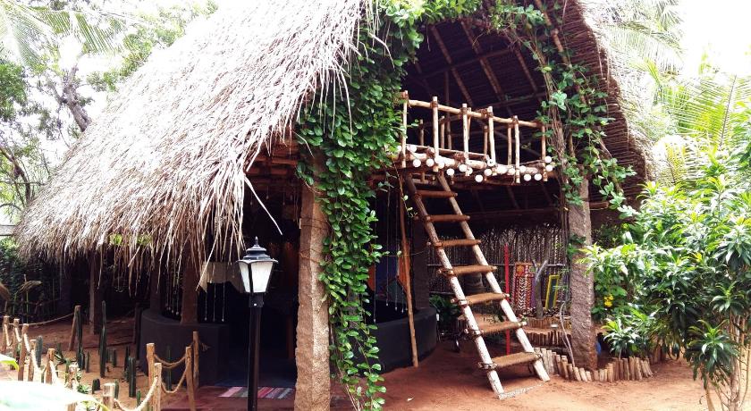 a large wooden structure with a tree, Dharmakanni Tropical Huts in Pondicherry