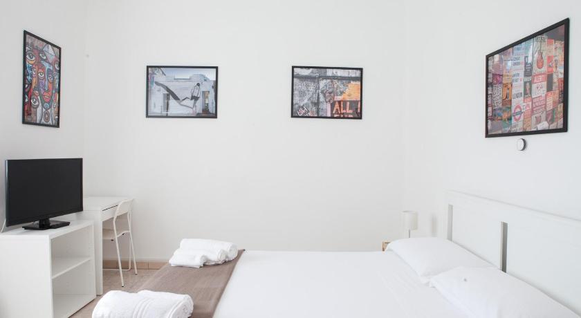 a living room with a bed, television and paintings on the wall, Residenza Cleopatra 1 in Ancona