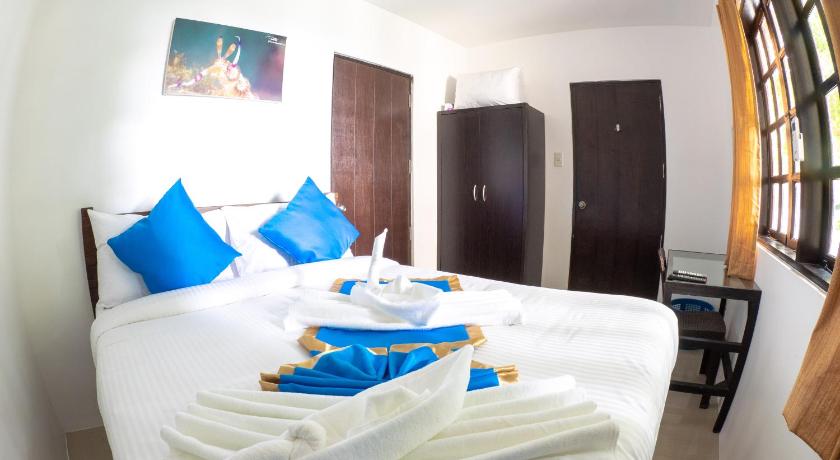 a bed with a white blanket and pillows on top of it, Blue Ribbon Dive Resort in Batangas