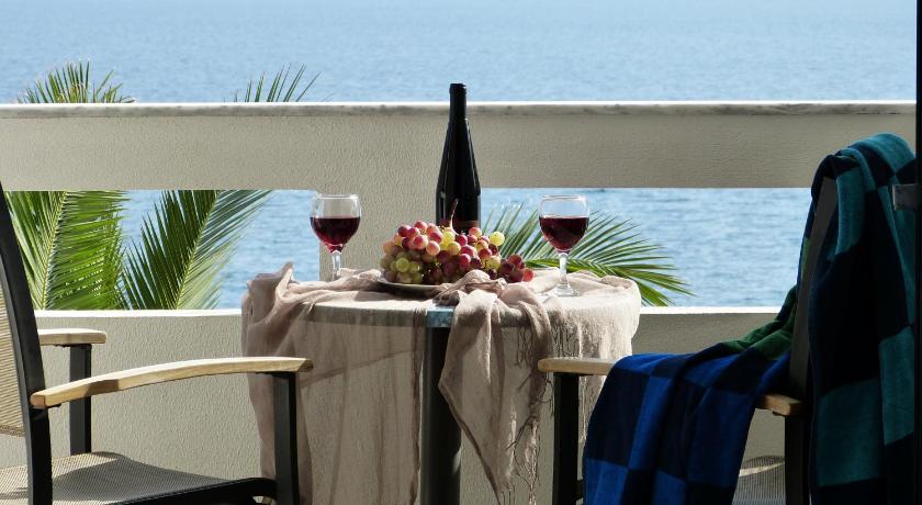a table with a glass of wine and a plate of food, Ostria Seaside Studios and Apartments in Chios