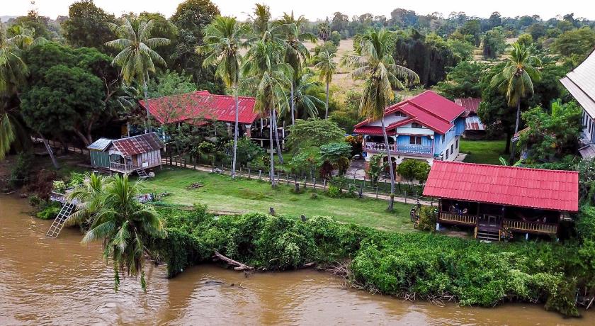 a red and white boat sitting on top of a lush green field, The Boathouse in Muang Khong