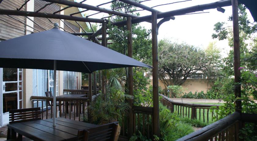a patio area with a table, chairs and umbrellas, Airport Inn Bed and Breakfast in Johannesburg