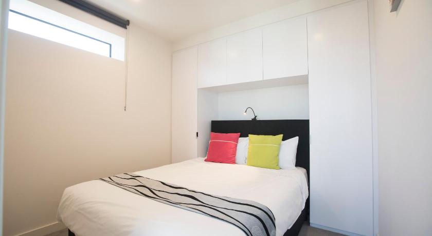 a bedroom with a white bed and white walls, Platinum City Serviced Apartments in Melbourne