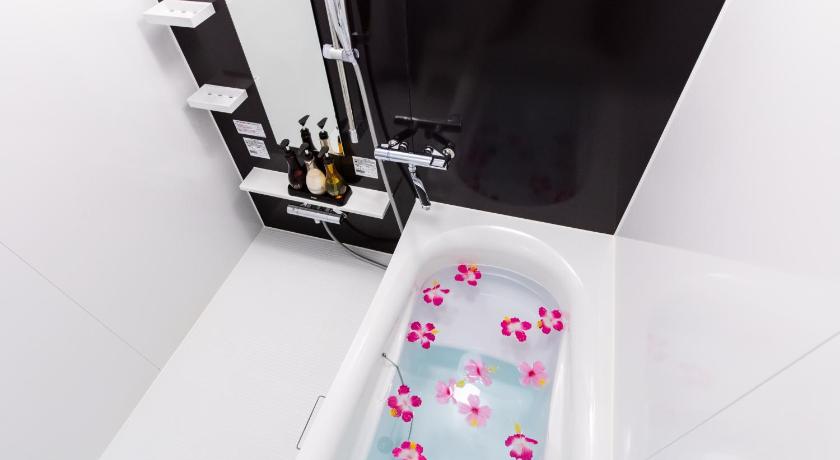 a bathroom with a tub and a shower curtain, Condominium Hotel Monpa in Okinawa Main island
