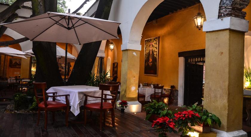 a patio area with a table, chairs, and umbrella, Suites Los Camilos in Mexico City