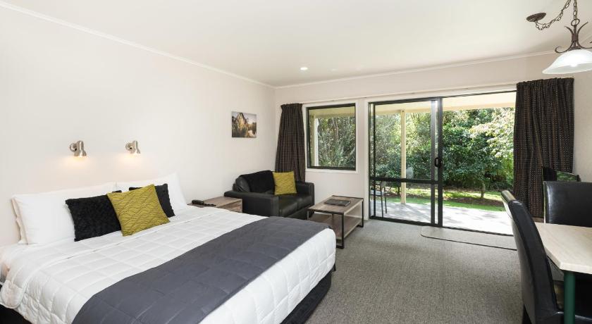 a bedroom with a large bed and a large window, Kauri Park Motel in Kerikeri