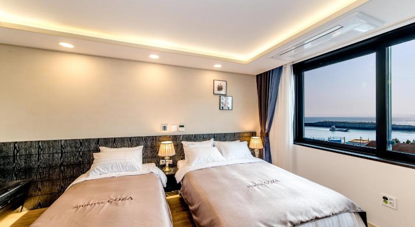 a hotel room with two beds and a television, Seawater Spa Hotel Coza in Jeju