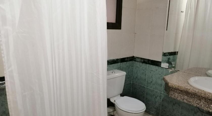 a white toilet sitting next to a bath tub in a bathroom, Regina Resort El Sokhna in Ataqah