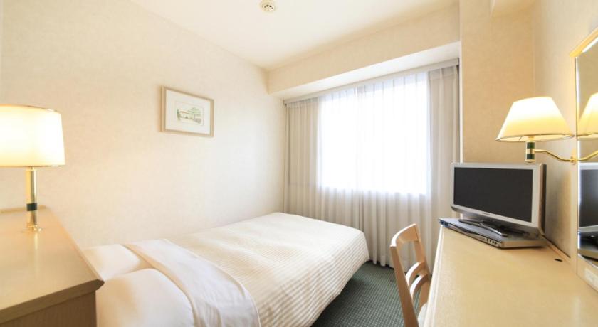 a hotel room with a bed, desk and television, Kofu Washington Hotel Plaza in Kofu