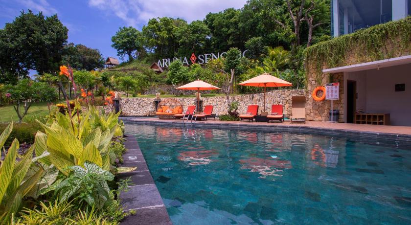 people are lounging in a pool with umbrellas, Aruna Senggigi Resort & Convention in Lombok