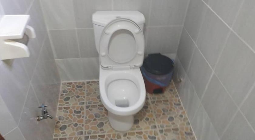 a white toilet sitting in a bathroom next to a trash can, Iz Village in Kampung Raja (Terengganu)