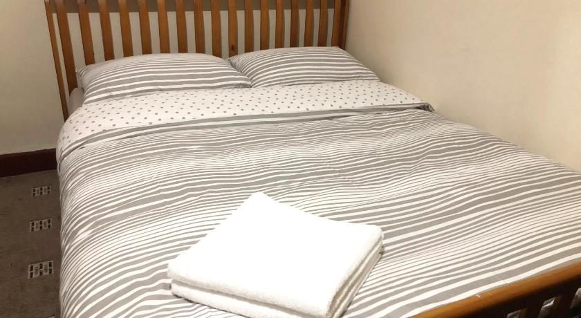 a bed with a white comforter and pillows on it, The Guest House in Luton