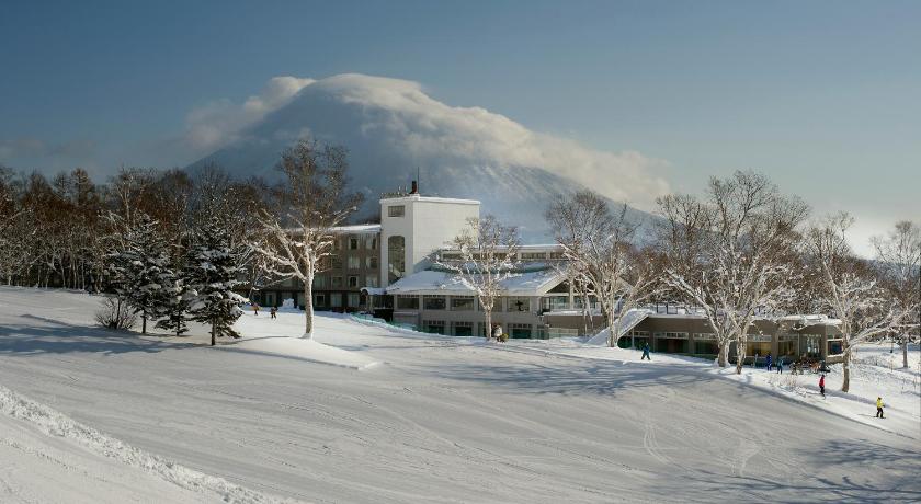 a snow covered ski slope with a building, The Green Leaf Niseko Village in Niseko