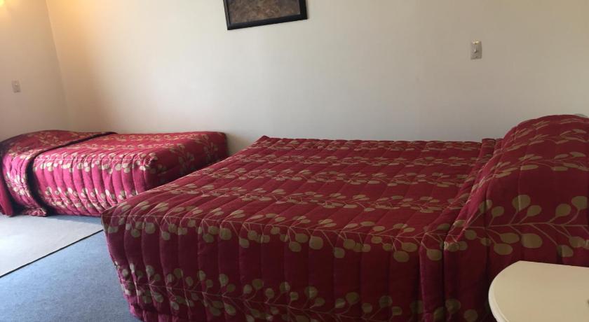 two red beds in a room with a red couch, Ploughman Motel in Levin