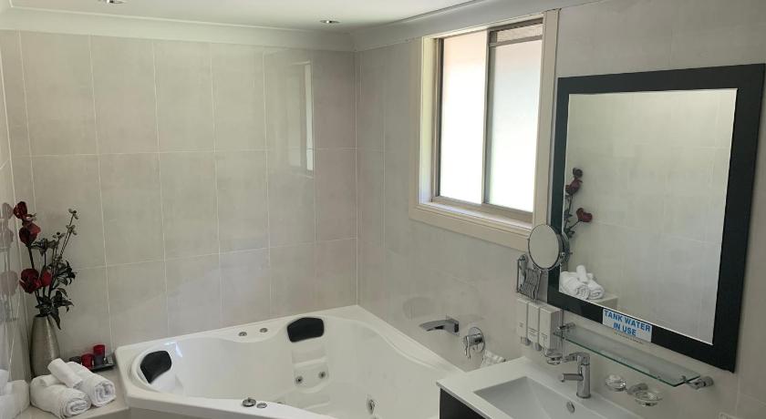 a bathroom with a tub, sink, mirror and bathtub, Picton Valley Motel in Picton (NSW)