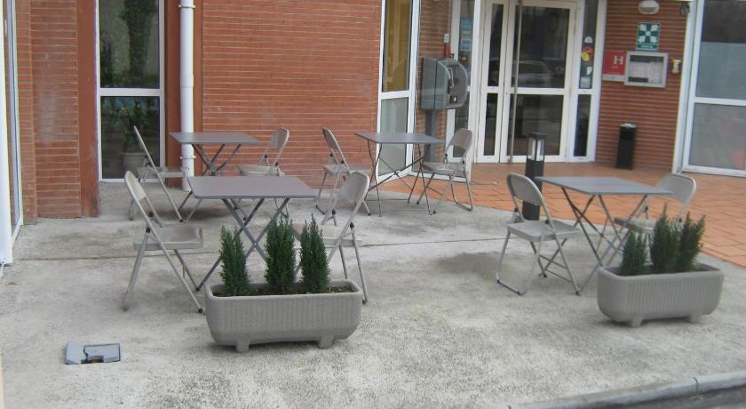 a patio area with chairs, tables and umbrellas, Premiere Classe Toulouse Sud - Labege Innopole in Labege