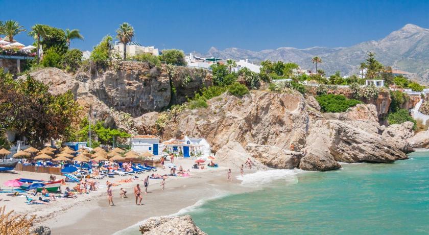 a beach filled with lots of beach chairs and umbrellas, Luna de Nerja in Nerja