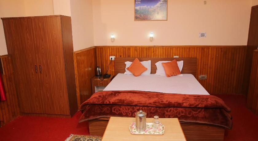 a room with a bed, a table, and a painting on the wall, Hotel Swagat Pelling in Pelling