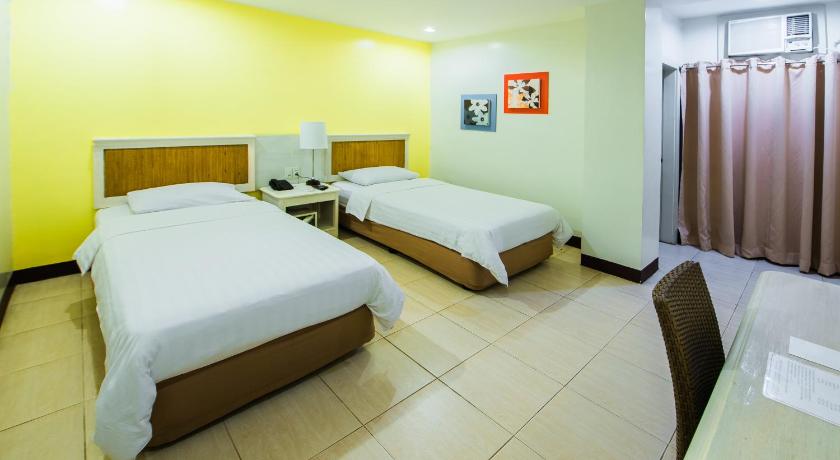 a hotel room with two beds and a television, L'Fisher Hotel in Bacolod (Negros Occidental)