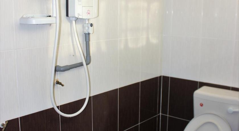 a white toilet sitting next to a shower in a bathroom, Homestay An-Najah in Temerloh