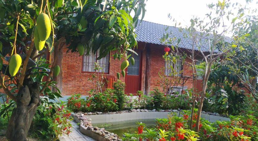 a brick building with a flower garden in front of it, Lang Chai Homestay in Phu Quoc Island