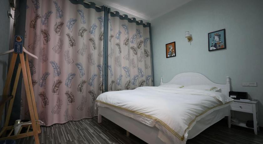 a bed in a room with a white bedspread, Yiju Inn in Wuhan