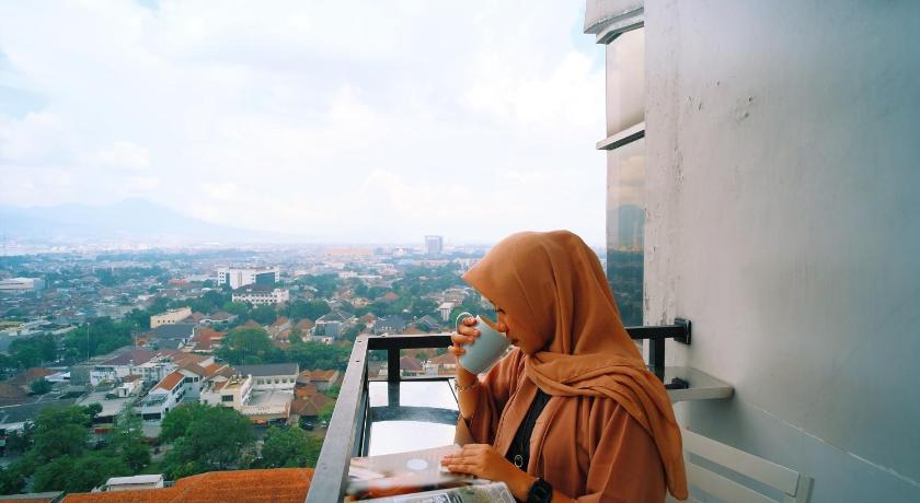 a woman sitting at a table in front of a building, INAP at Capsule Hostel in Bandung