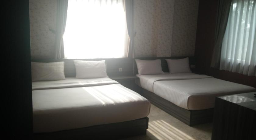 a hotel room with two beds and a window, Tulip Guest House in Bandung