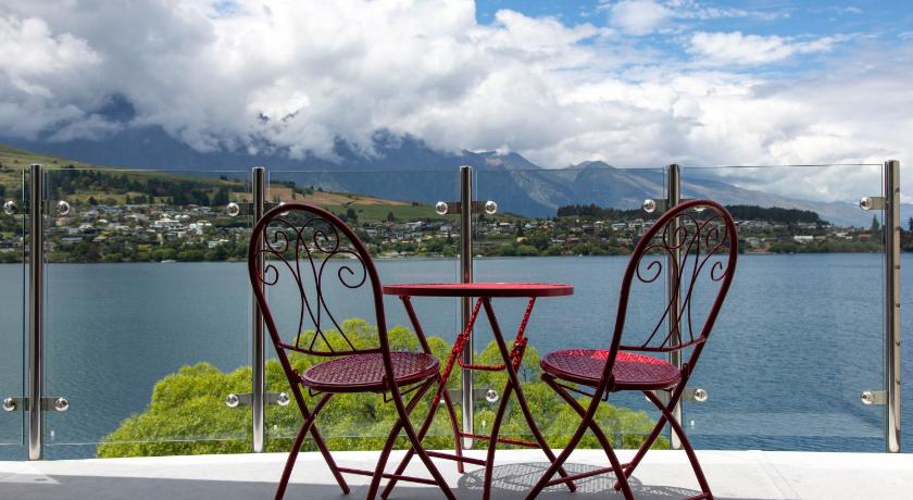 a table with chairs and a bench in front of a lake, BreakFree The Point Queenstown in Queenstown