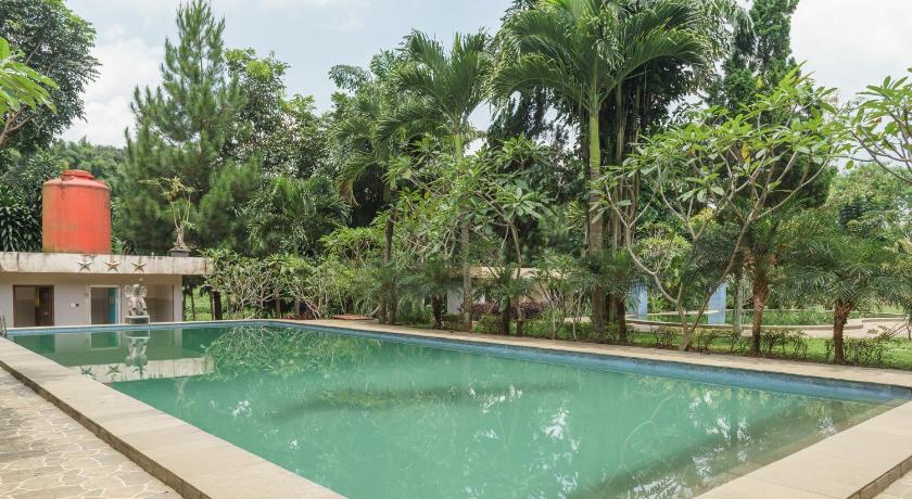 a large pool of water surrounded by palm trees, RedDoorz Plus @ Lodaya Gunung Geulis Puncak in Puncak