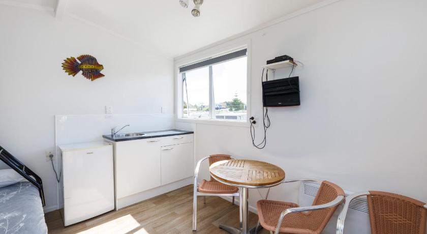 a kitchen with a table, chairs and a refrigerator, Foxton Beach Holiday Park in Foxton Beach