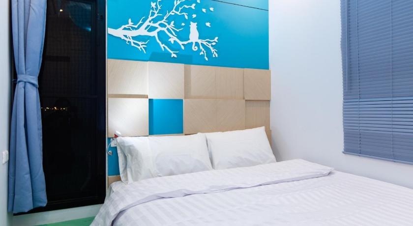 a bedroom with a white bed and a blue wall, Lilliput Riverside Bangkachao in Bangkok