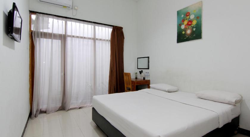 a bedroom with a white bed and white walls, The Fort Hotel in Yogyakarta